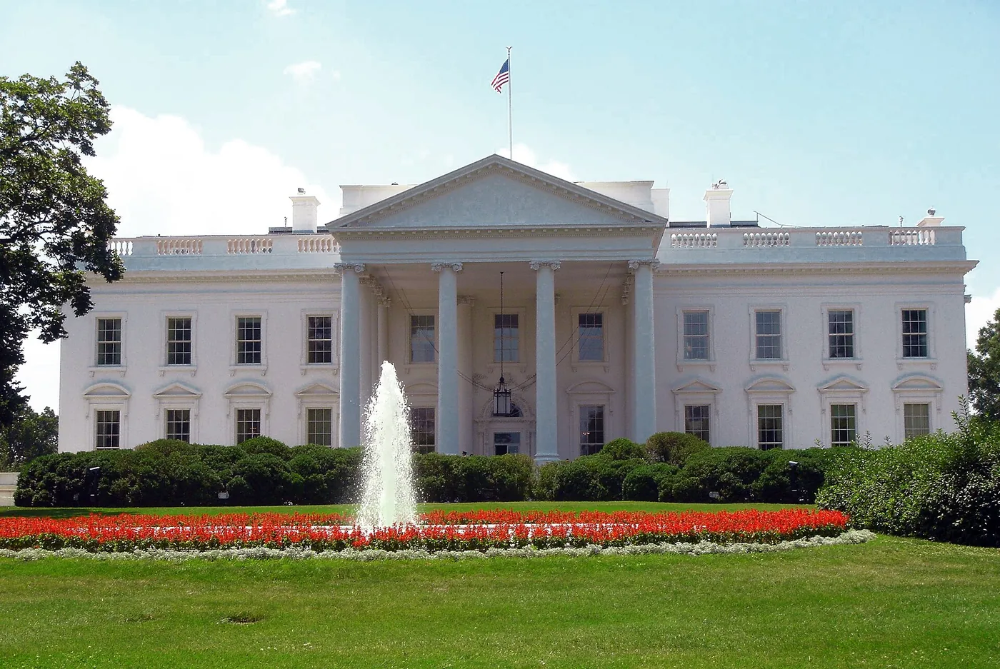 The north facade of the White House in Washington, D.C., with its columned portico, fountain and lawn on a clear day.